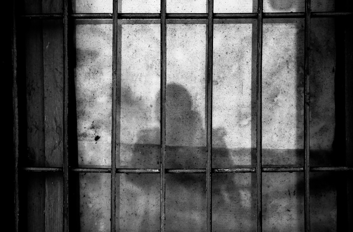 Shadow of a person cast through prison bars — incarcerated people and their families pay monopoly prices to stay connected